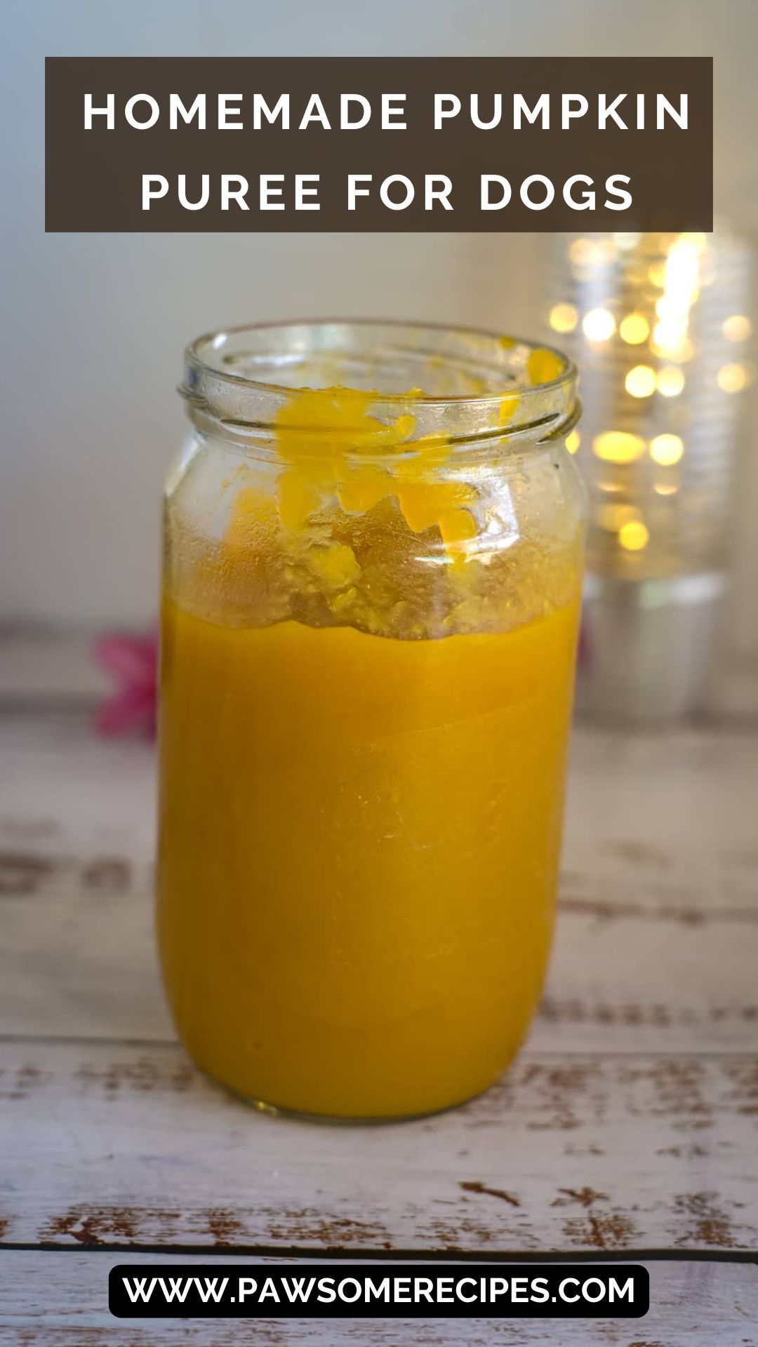 A glass jar filled with pumpkin puree for dogs sits on a light wooden surface. Text on the image reads "Homemade pumpkin puree for dogs" and "www.pawsomerecipes.com".