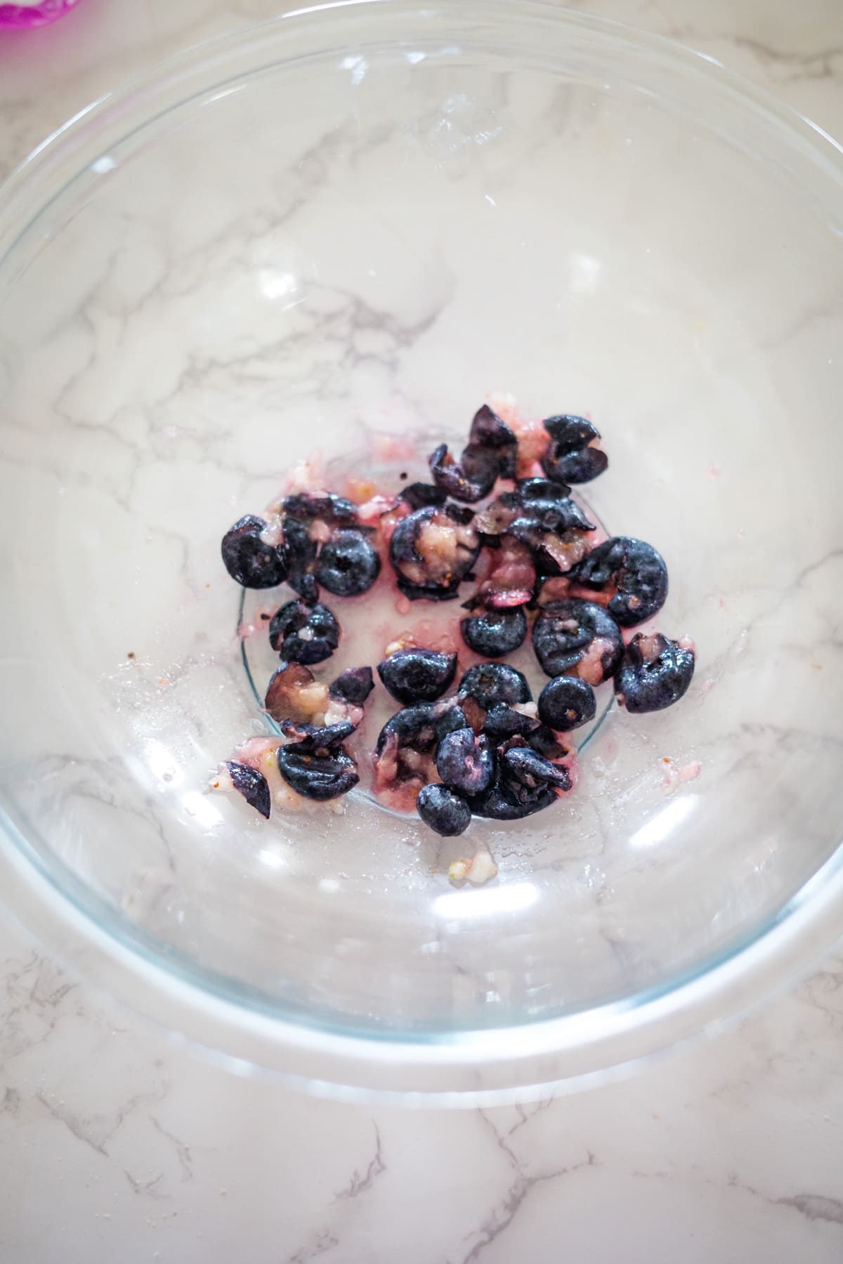 Glass bowl with halved dark cherries on a marble surface, nestled beside blueberry yogurt dog treats.