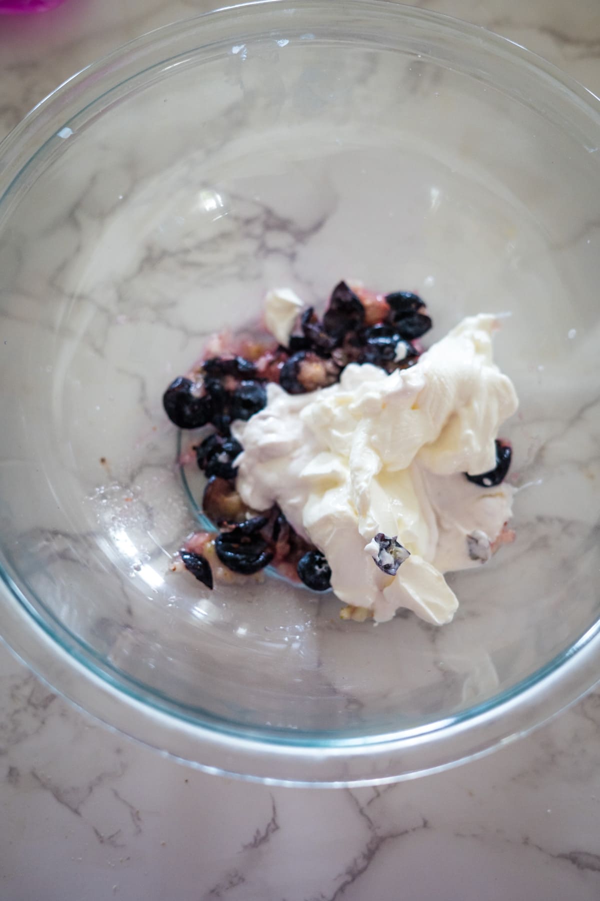 A glass bowl on a marble surface contains blueberries and a dollop of creamy blueberry yogurt, tempting enough for even the pickiest eaters.