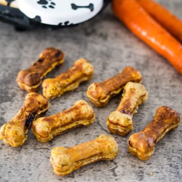 A tray of dog treats with carrots and carrot sticks.