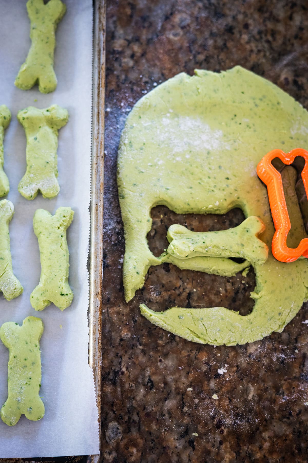 A cookie cutter is being used to make cookies with green frosting.