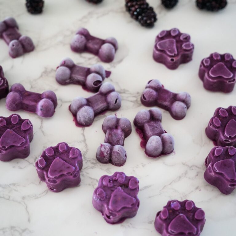 Purple paw-shaped candies scattered on a marble surface, varying in shades from light lavender to dark purple.
