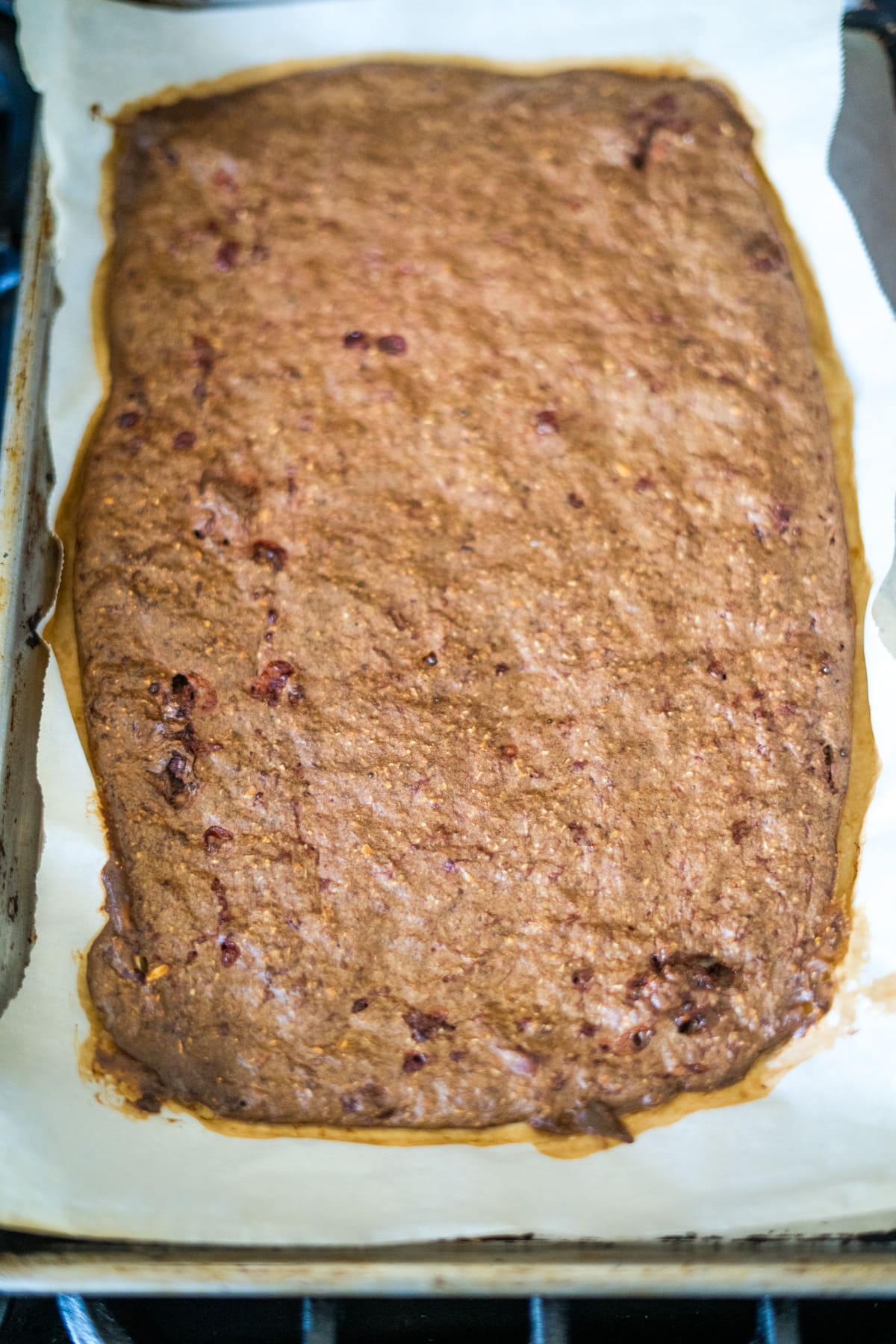 A rectangular baked loaf on parchment paper in a baking tray.