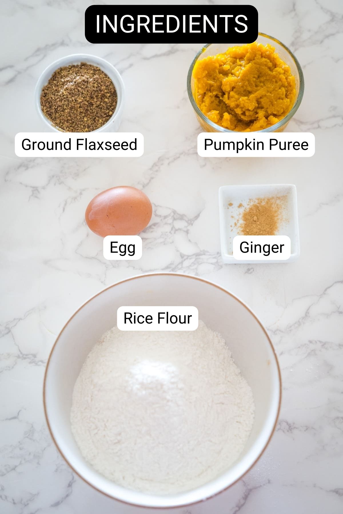 Ingredients on a marble surface: Ground flaxseed, pumpkin puree, one egg, powdered ginger, and rice flour.