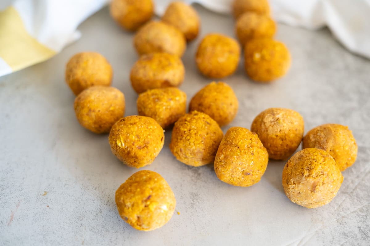 Golden-brown round energy bites arranged on a light gray surface.