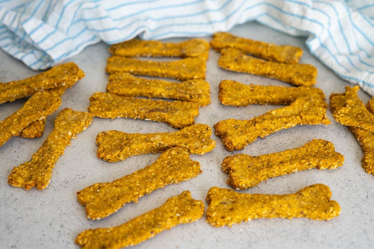 Bone-shaped dog biscuits arranged on a worktop with a blue and white striped cloth in the background.