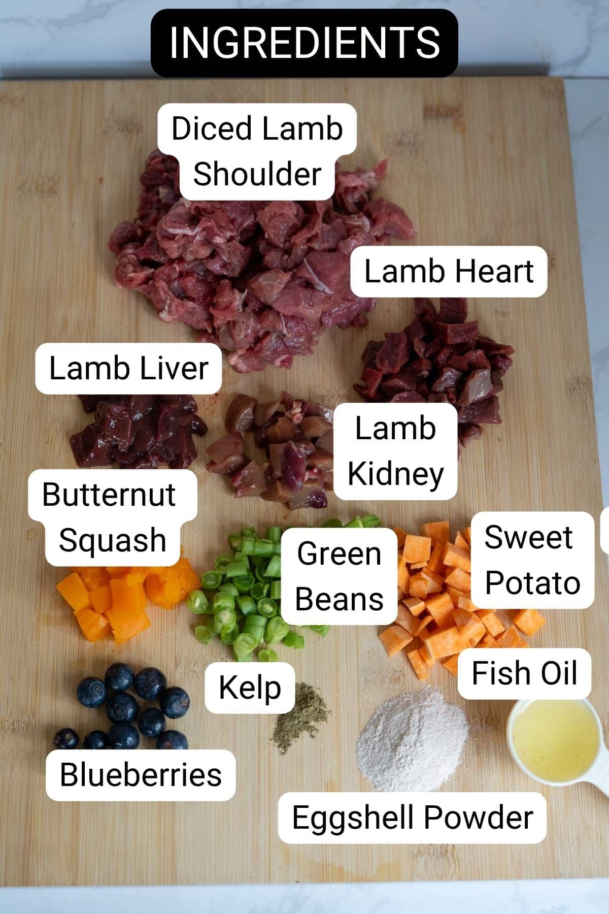 Chopped lamb shoulder, heart, liver, kidney, and vegetables come together in this wholesome lamb stew for dogs—featuring butternut squash, green beans, sweet potato, blueberries, kelp, fish oil, and eggshell powder on a wooden board.