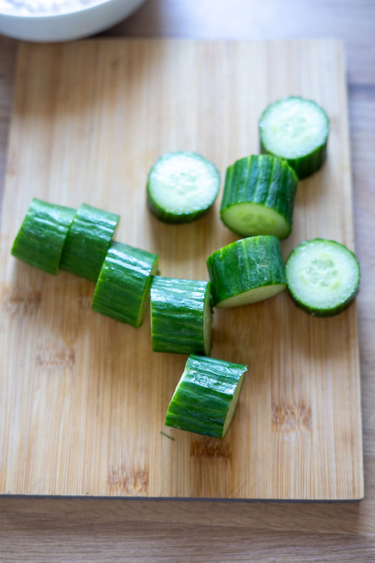Sliced cucumber pieces arranged on a wooden chopping board.