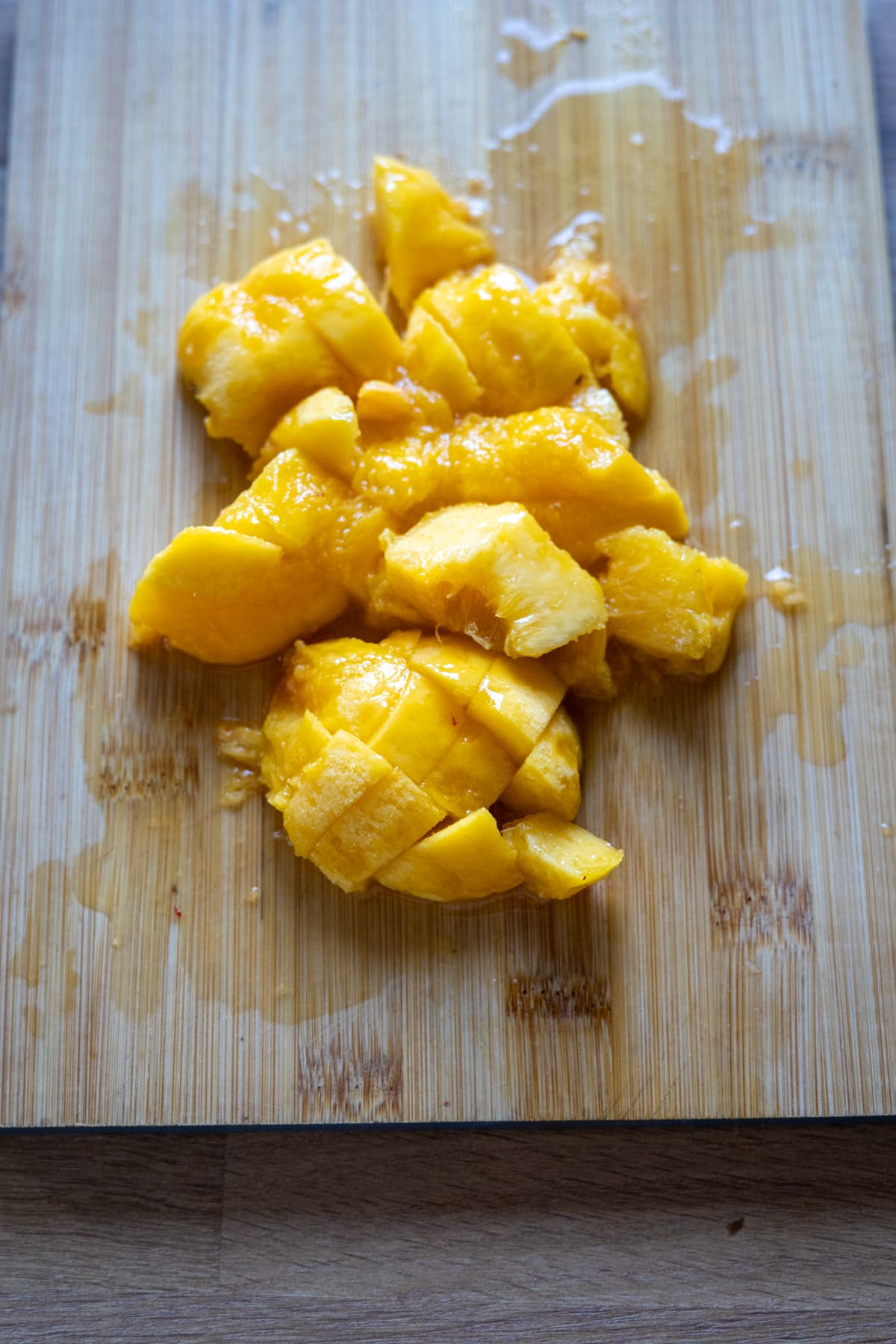 Chopped pieces of mango on a wooden chopping board.