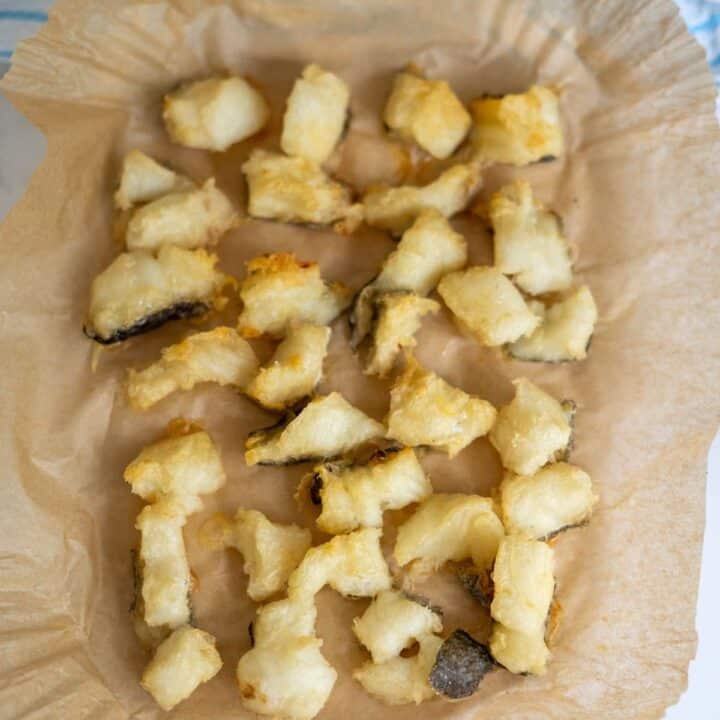Battered and fried fish pieces arranged on greaseproof paper.