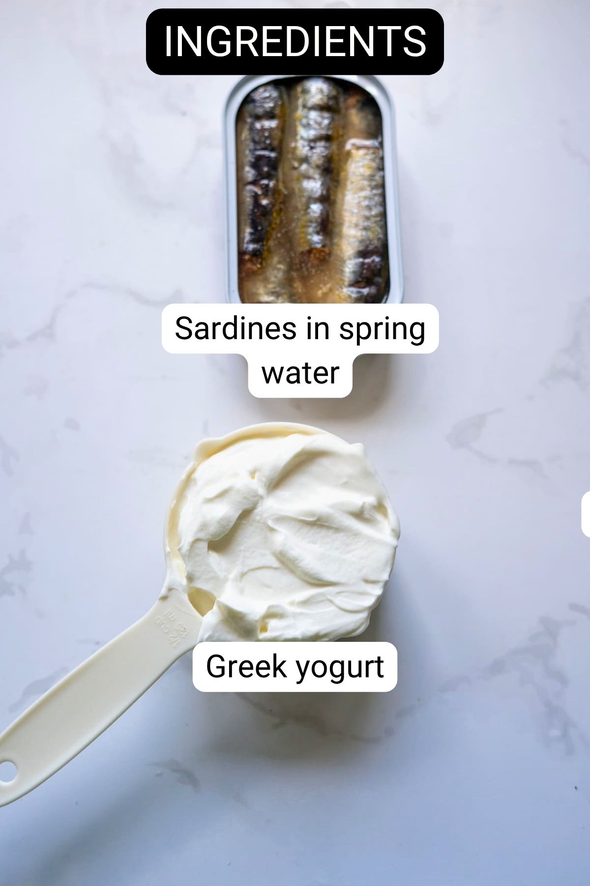 A tin of sardines in spring water and a measuring jug of Greek yoghurt are labelled as ingredients for sardine ice cream on a white surface.
