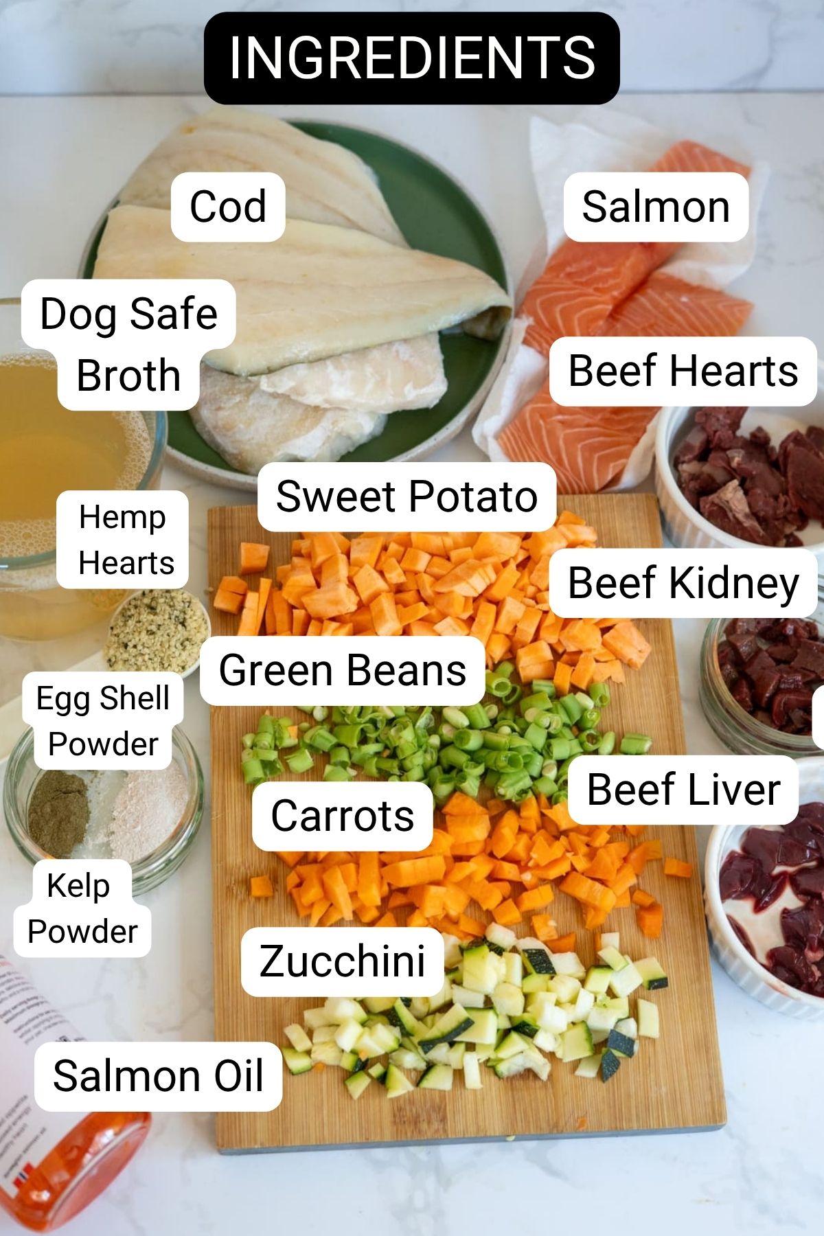 Chopped vegetables, raw fish, offal, powders, and stock—perfect components for a nourishing fish stew for dogs—are labelled as dog food ingredients on a worktop.