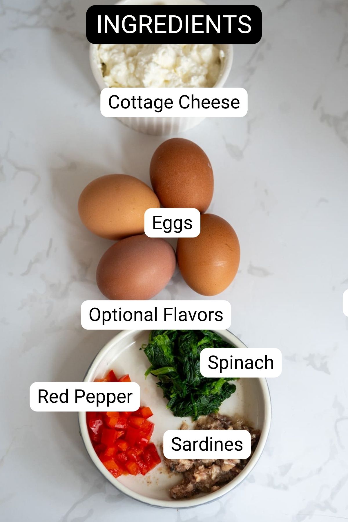Cottage cheese, eggs, red pepper, spinach, and sardines are arranged on a marble surface, labelled as ingredients and optional flavours for a recipe—perfect for making nutritious egg bites for dogs.