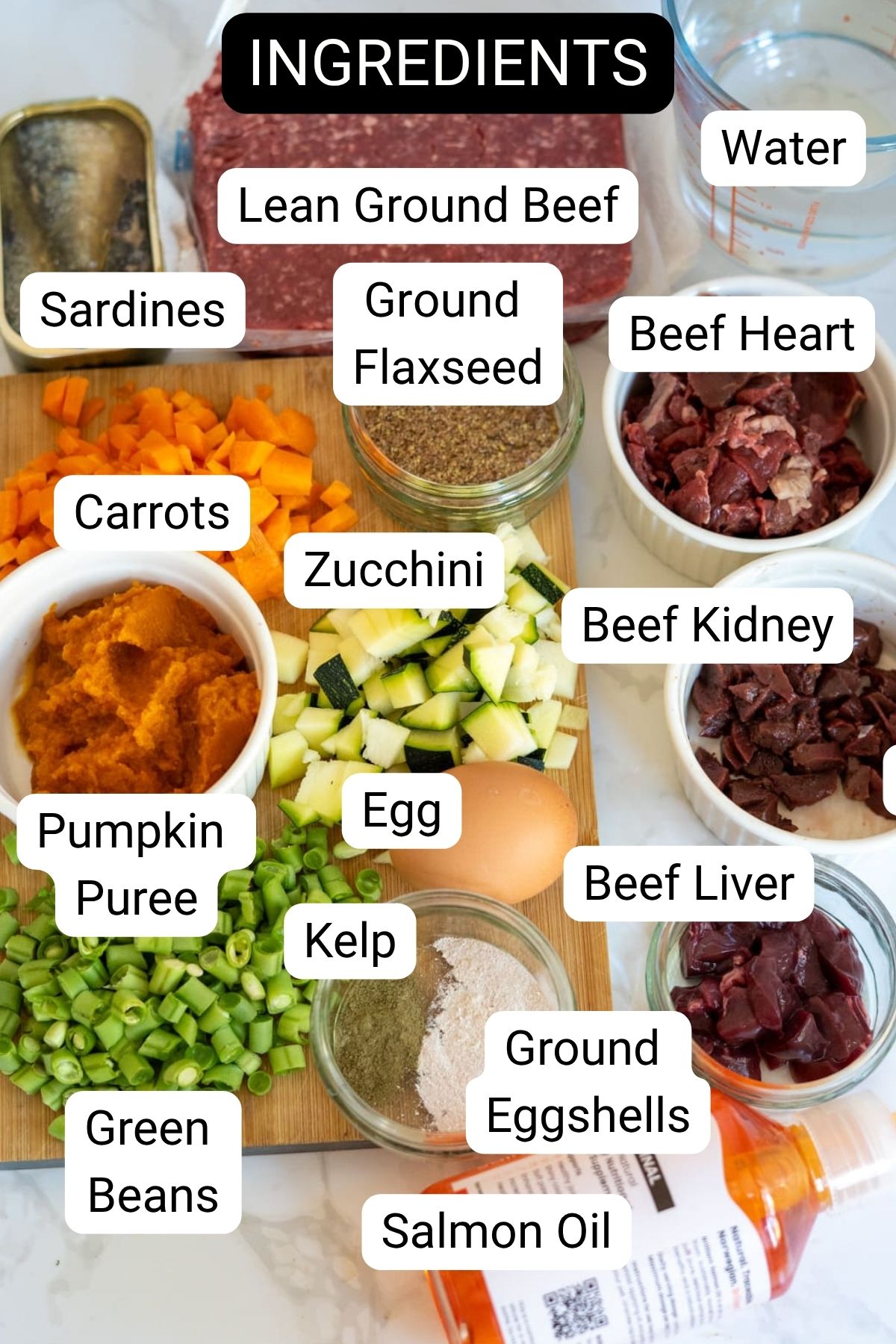 A variety of labelled ingredients for a homemade dog food recipe, perfect for Slow Cooker Beef Dog Food, including meats, vegetables, seeds, eggs, and supplements, arranged on a counter.