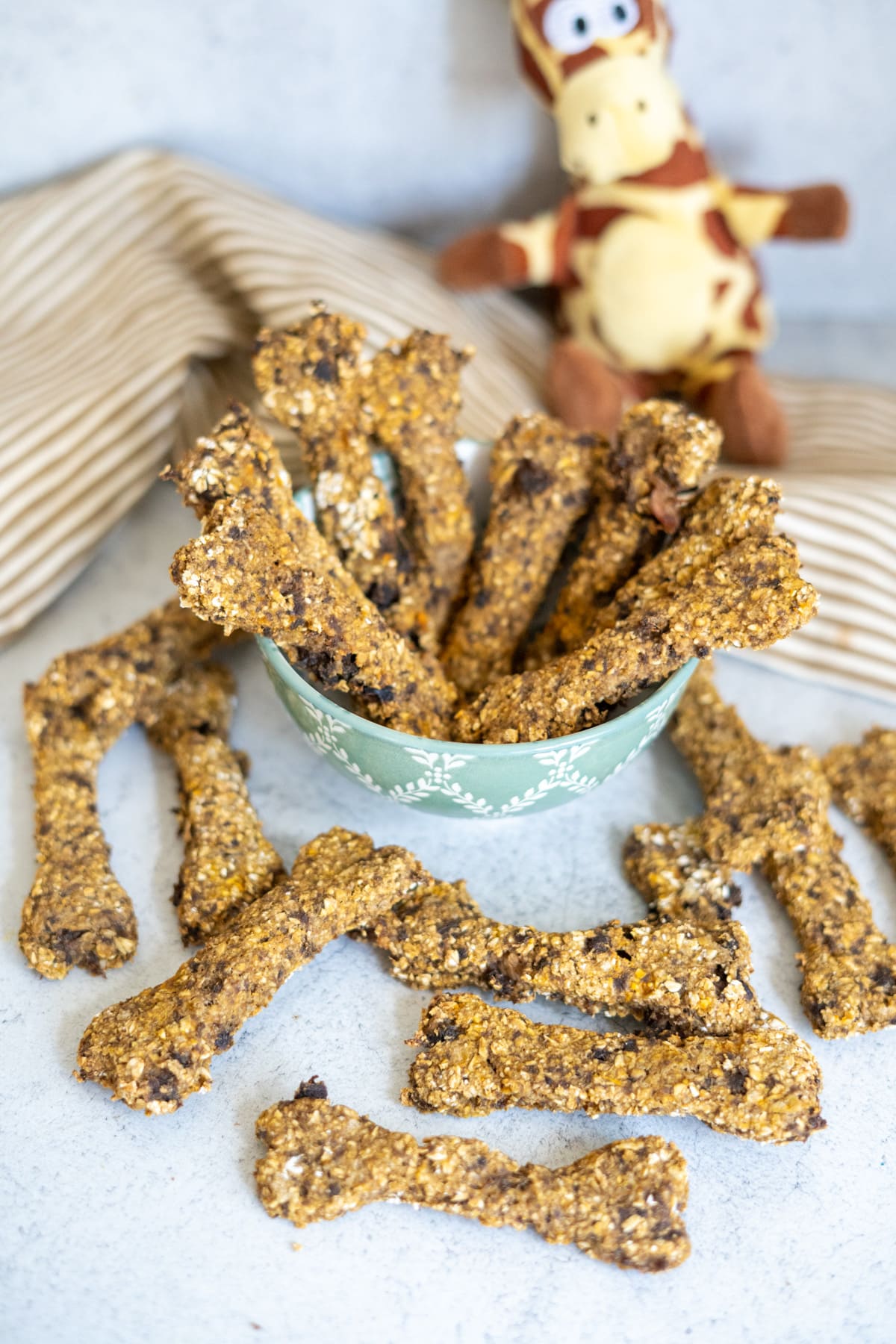Lamb and sweet potato dog treats in and around a patterned bowl.