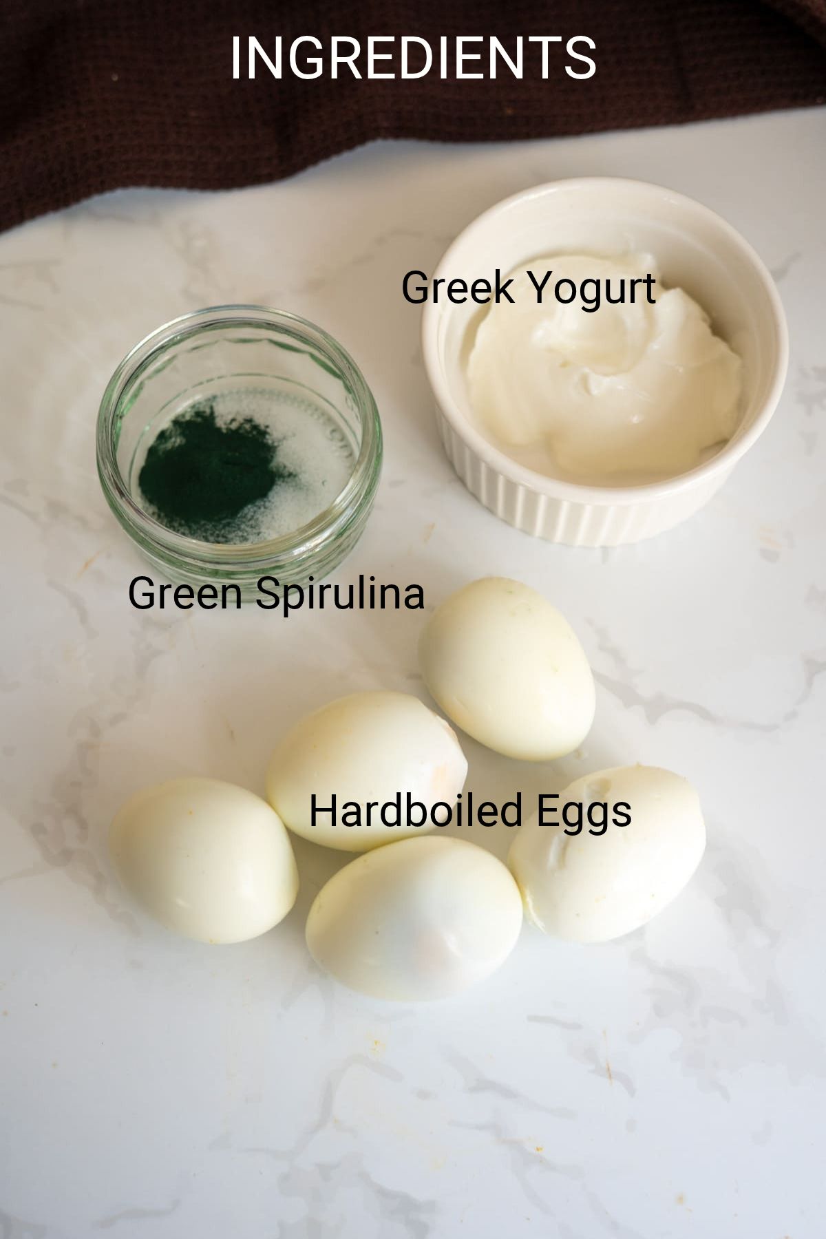 A bowl of Greek yoghurt, a small jar of green spirulina powder, and five hard-boiled eggs used to make Hallowe’en devilled eggs for dogs.