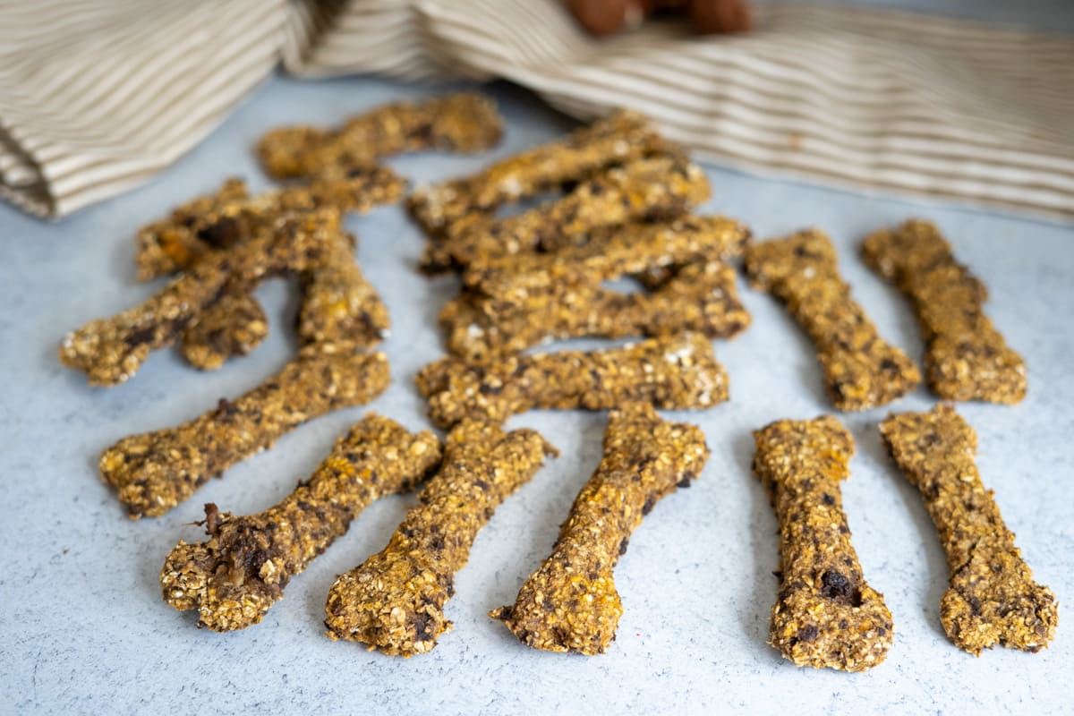 A cluster of homemade lamb and sweet potato dog treats shaped like bones on a light-coloured surface.