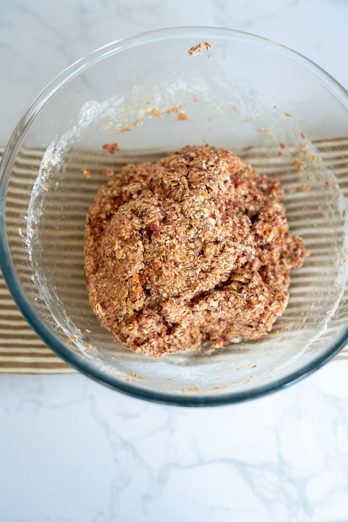 A glass bowl containing a ball of raw dough for lamb and sweet potato dog treats.