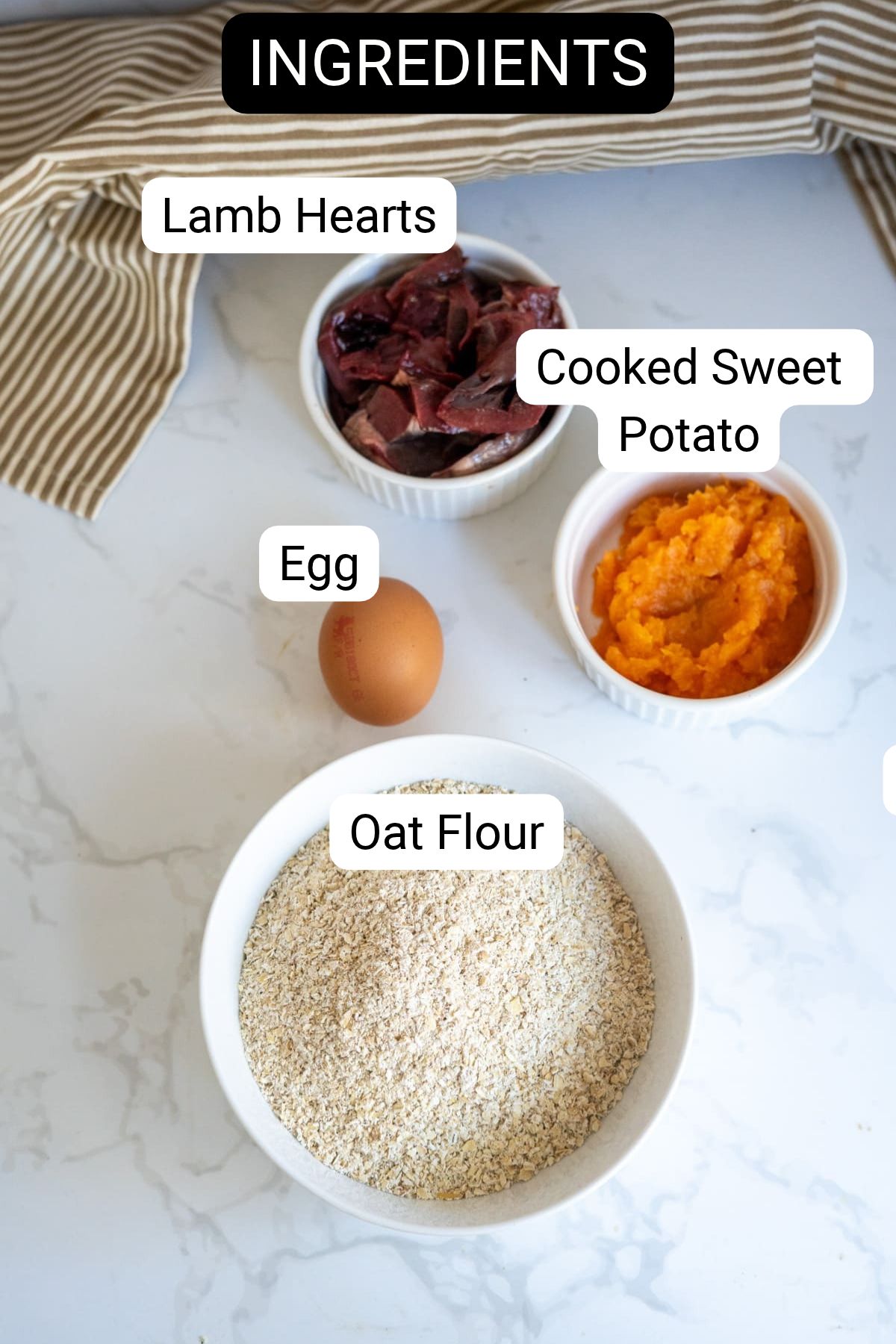 Ingredients for lamb and sweet potato dog treats, including lamb hearts, cooked sweet potato, an egg, and oat flour displayed in separate bowls.
