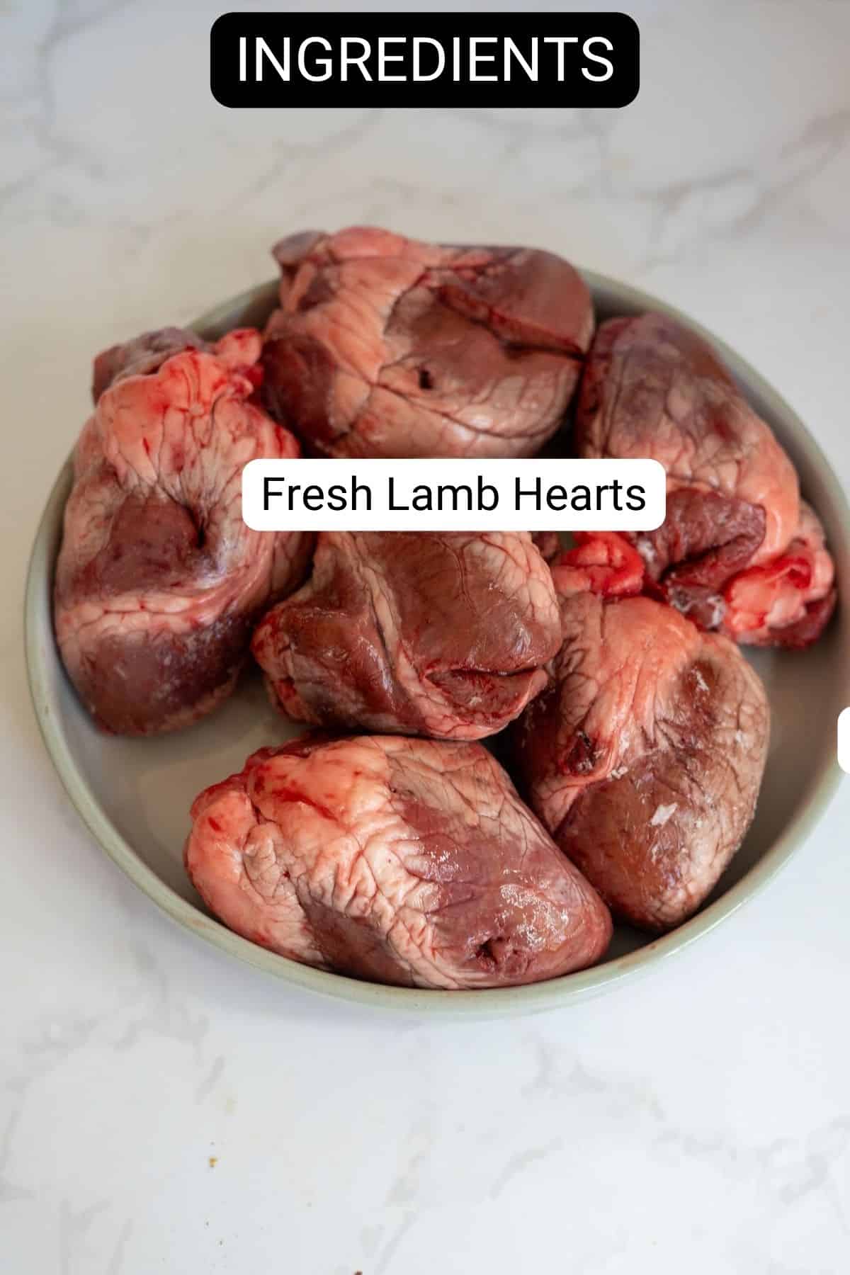 A plate of raw lamb hearts for dog treats with text overlays reading “INGREDIENTS” and “Fresh Lamb Hearts”.