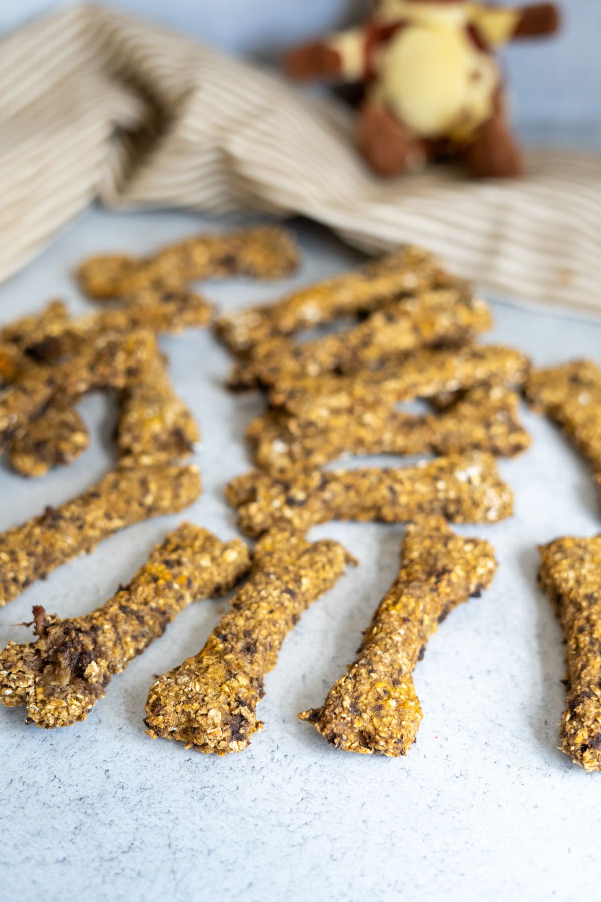 Several lamb and sweet potato bone-shaped dog biscuits scattered on a surface.